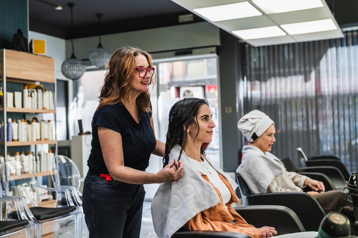 Hairdresser preparing a young woman's hair for a beauty treatment in a modern salon
