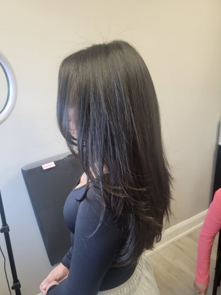 Woman with long dark layered hair viewed from behind, wearing a dark navy top